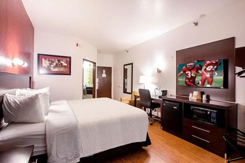 A hotel room with a king-sized bed, desk, and TV.